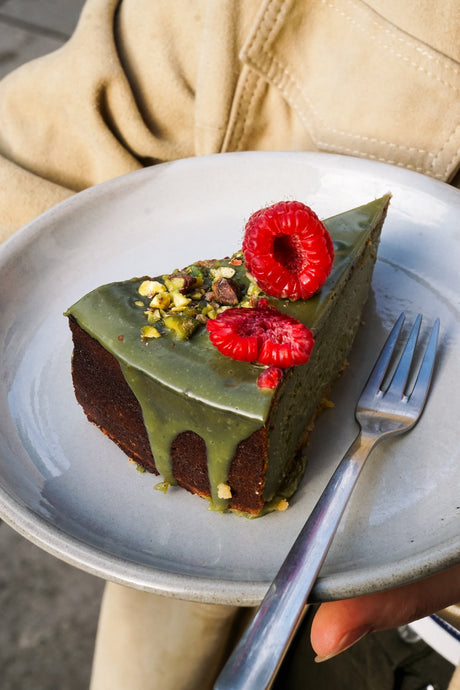 Kawałek ciasta matcha z malinami i pistacjami Batida na talerzu