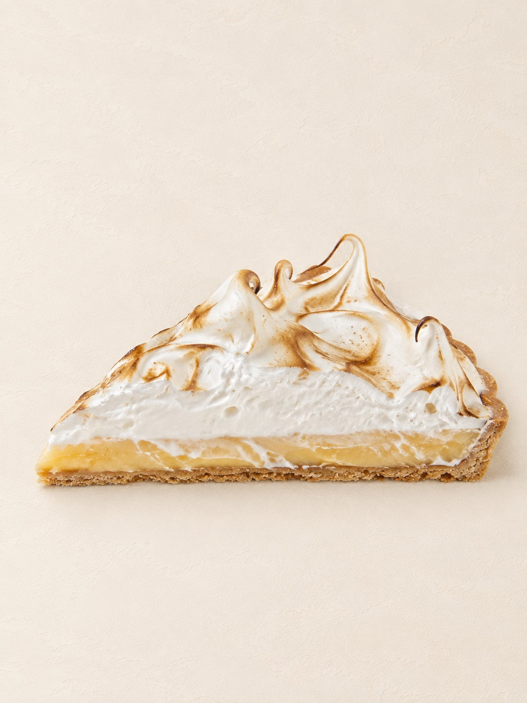 Tarte Zitrone - Yuzu mit flambiertem Baiser von Batida - ein Stück Tarte, Curd und Baiser im Querschnitt sichtbar