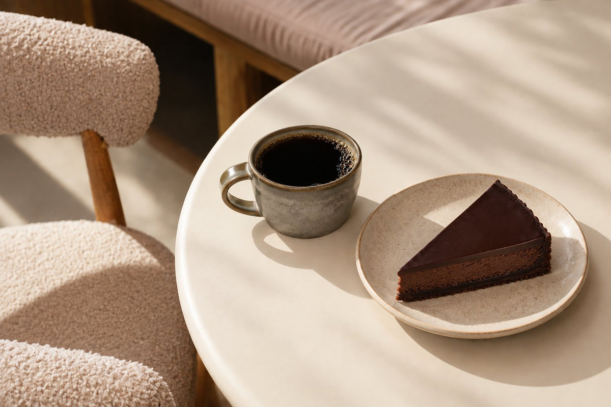 Filiżanka czarnej kawy i kawałek tarty czekoladowej na stoliku w jasnej kawiarni - pairing deseru z kawą, Batida