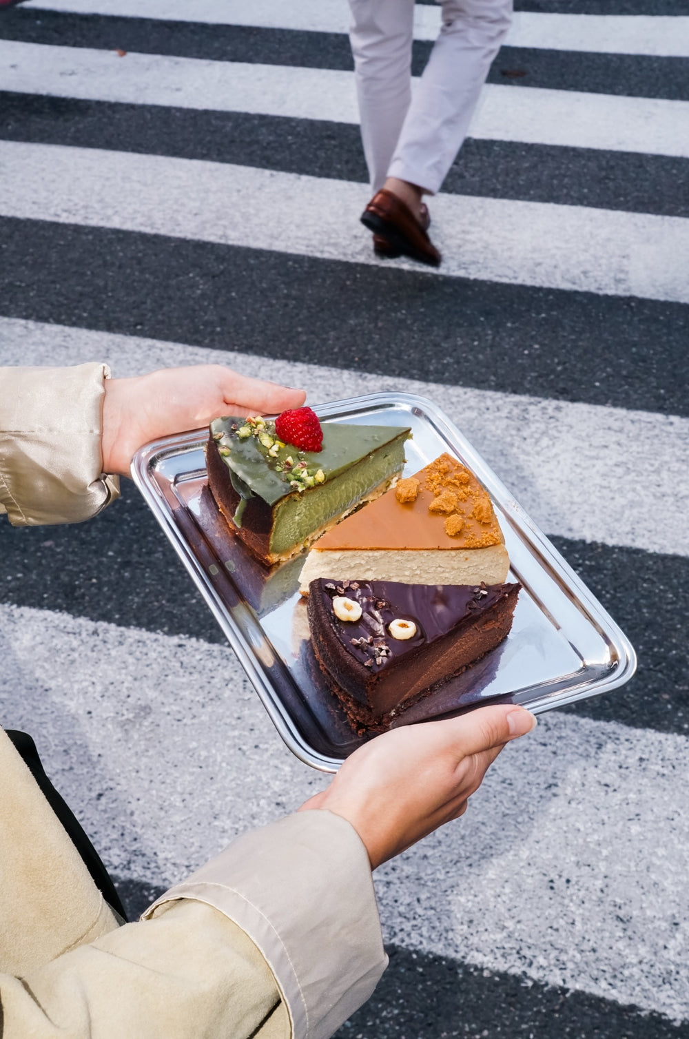Tablett mit Stücken der Batida-Käsekuchen: Matcha-, Lotus- und Schokoladenkäsekuchen über den Fahrbahnmarkierungen