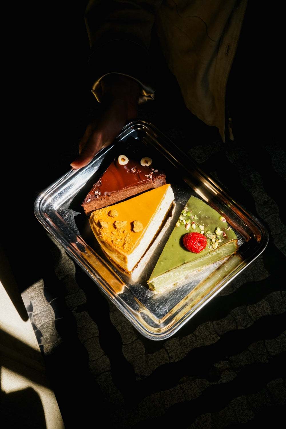 Drei Stücke Batida-Käsekuchen auf einem Tablett, Draufsicht auf dunklem Hintergrund