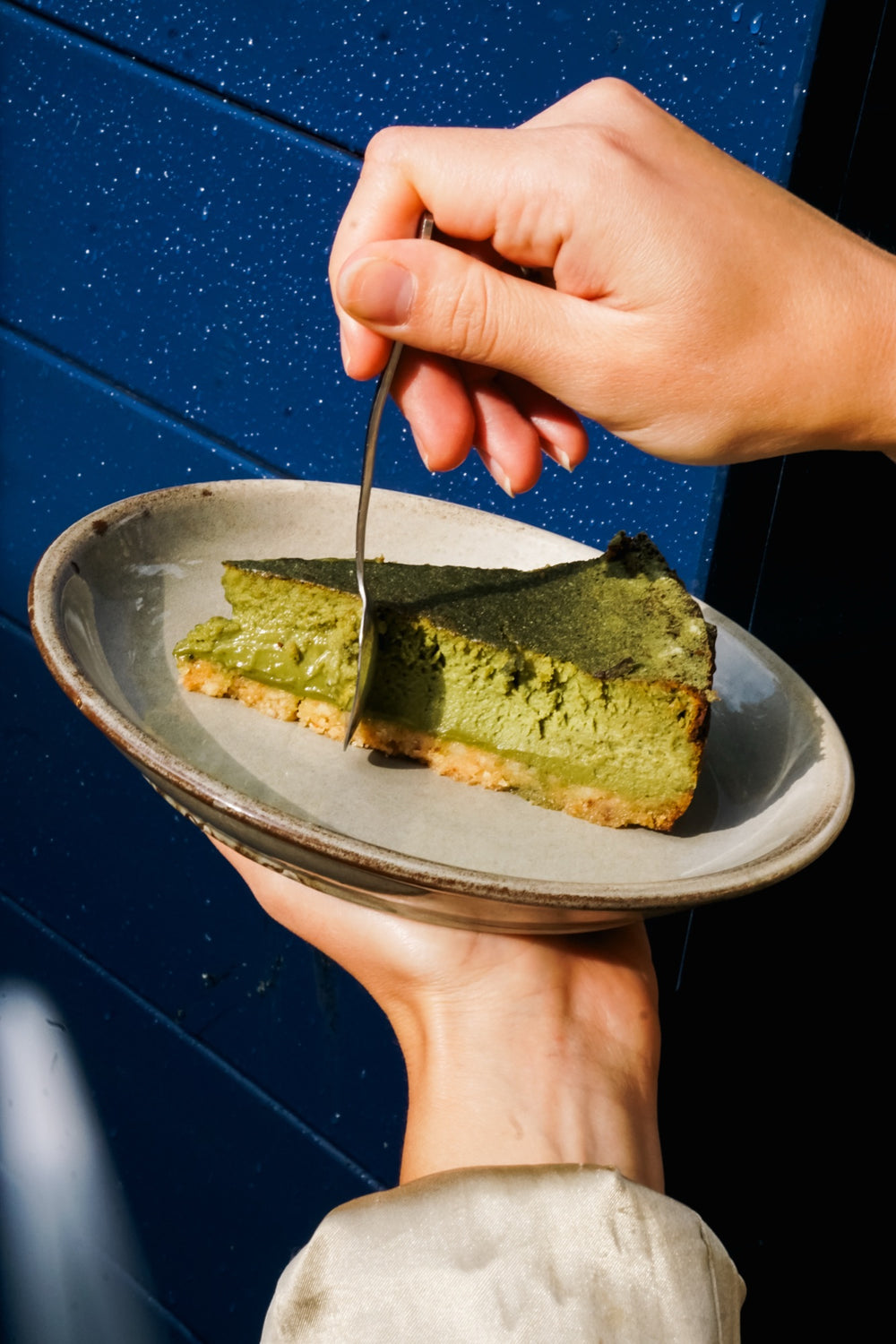 Matcha-Käsekuchen Batida auf einem Teller vor einer blauen Wand