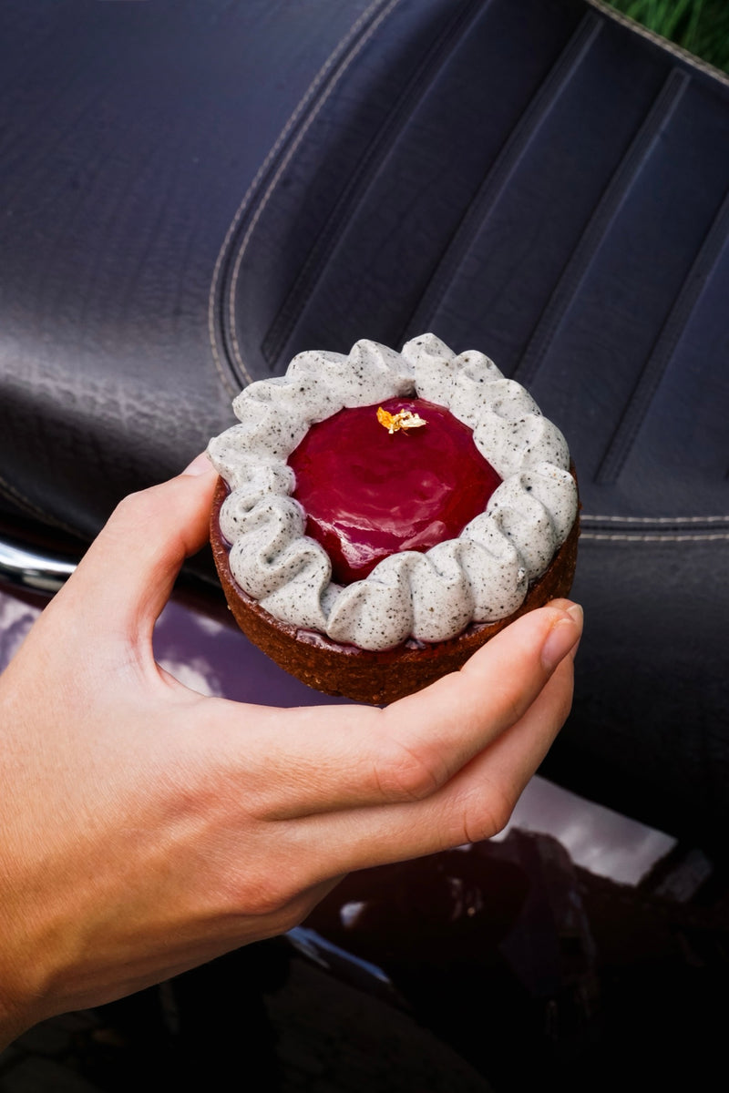 Batida Tartelette mit schwarzem Sesam in der Hand vor dunklem Hintergrund