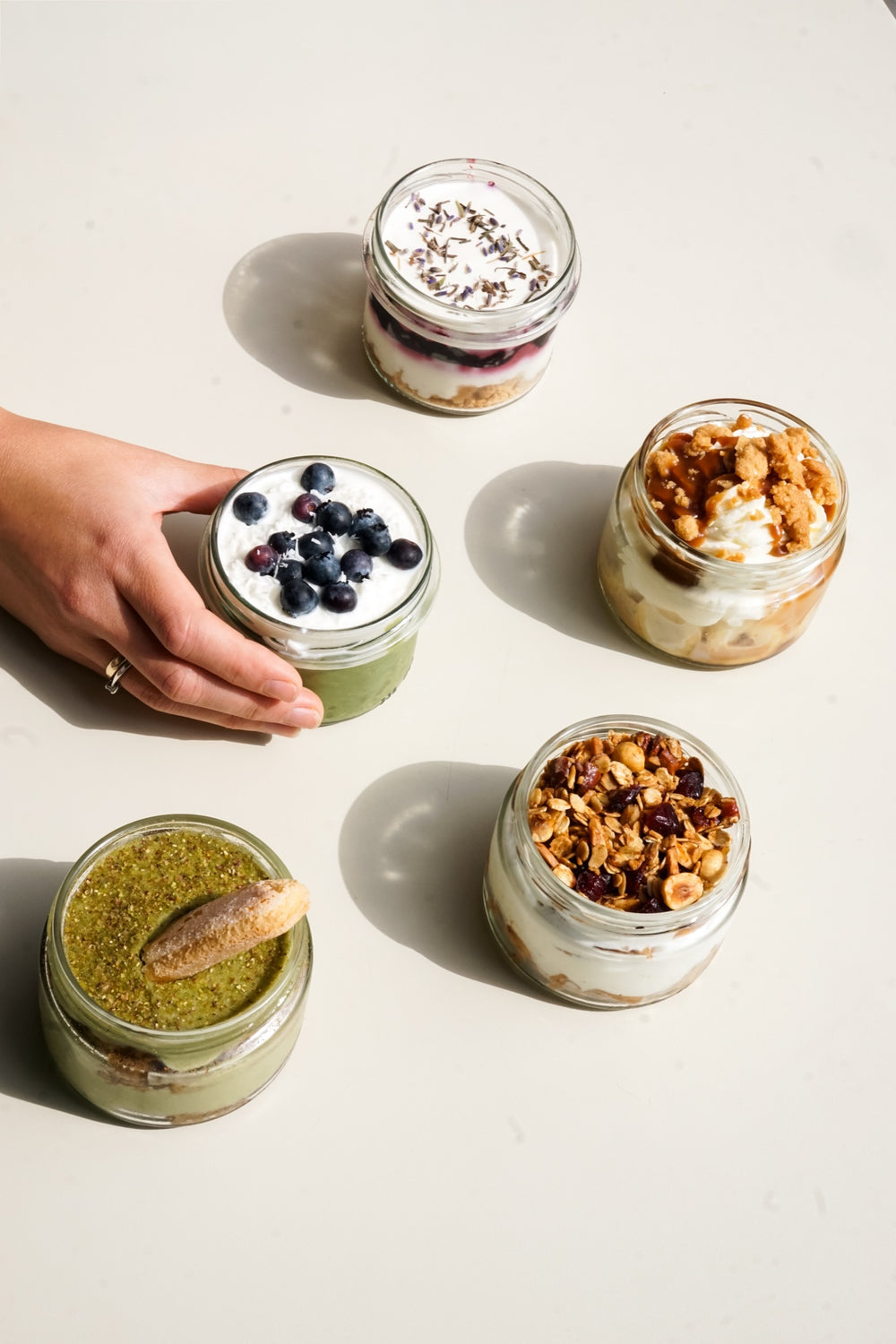 Fünf Batida-Desserts in Gläsern auf einem hellen Tisch