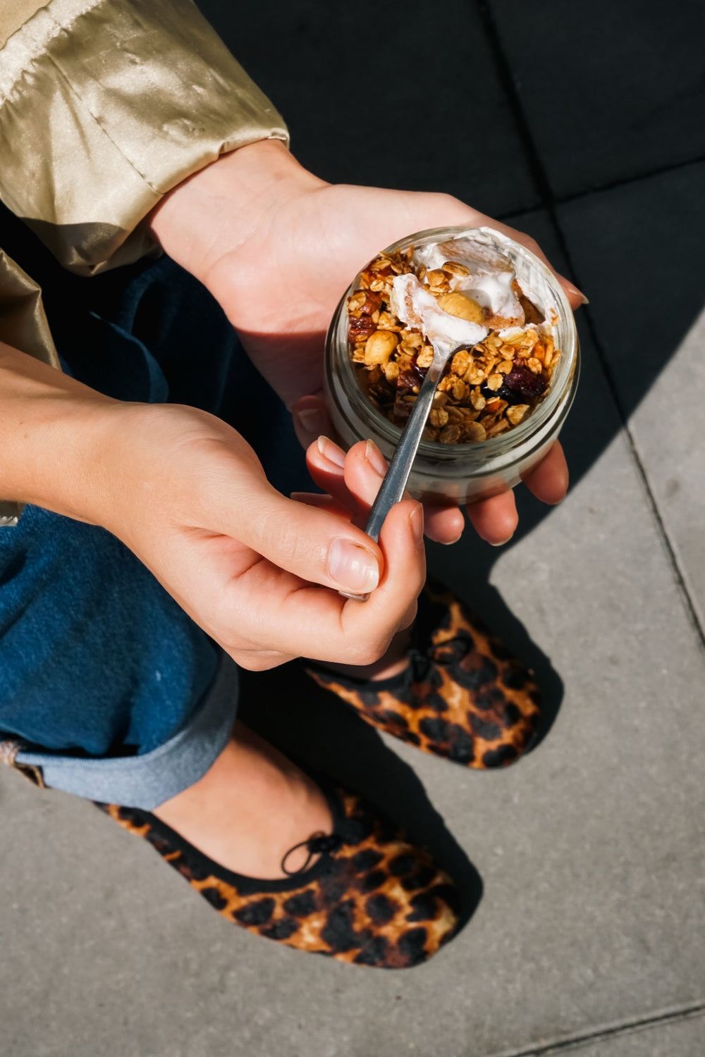 Batida-Dessert im Glas mit Granola und Creme, in den Händen gehalten