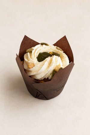 Muffin Marchew z kardamonem Batida - muffinka w brązowej papilotce, z kremem i pestkami dyni