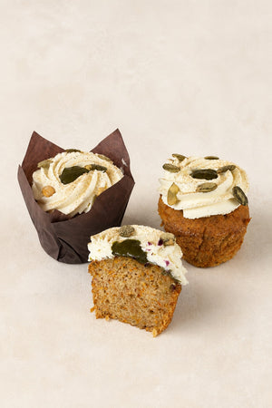Muffin Marchew z kardamonem Batida - dwie muffinki, w papilotce i bez, oraz połówka z widocznym przekrojem