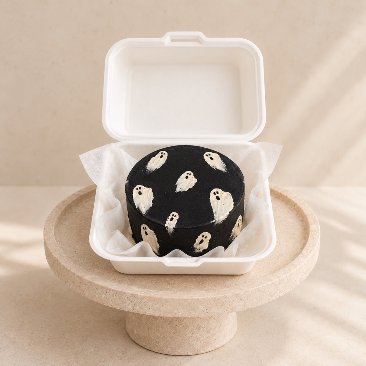 Schwarze Bento-Minitorte mit handgemalten Geistern in der Box