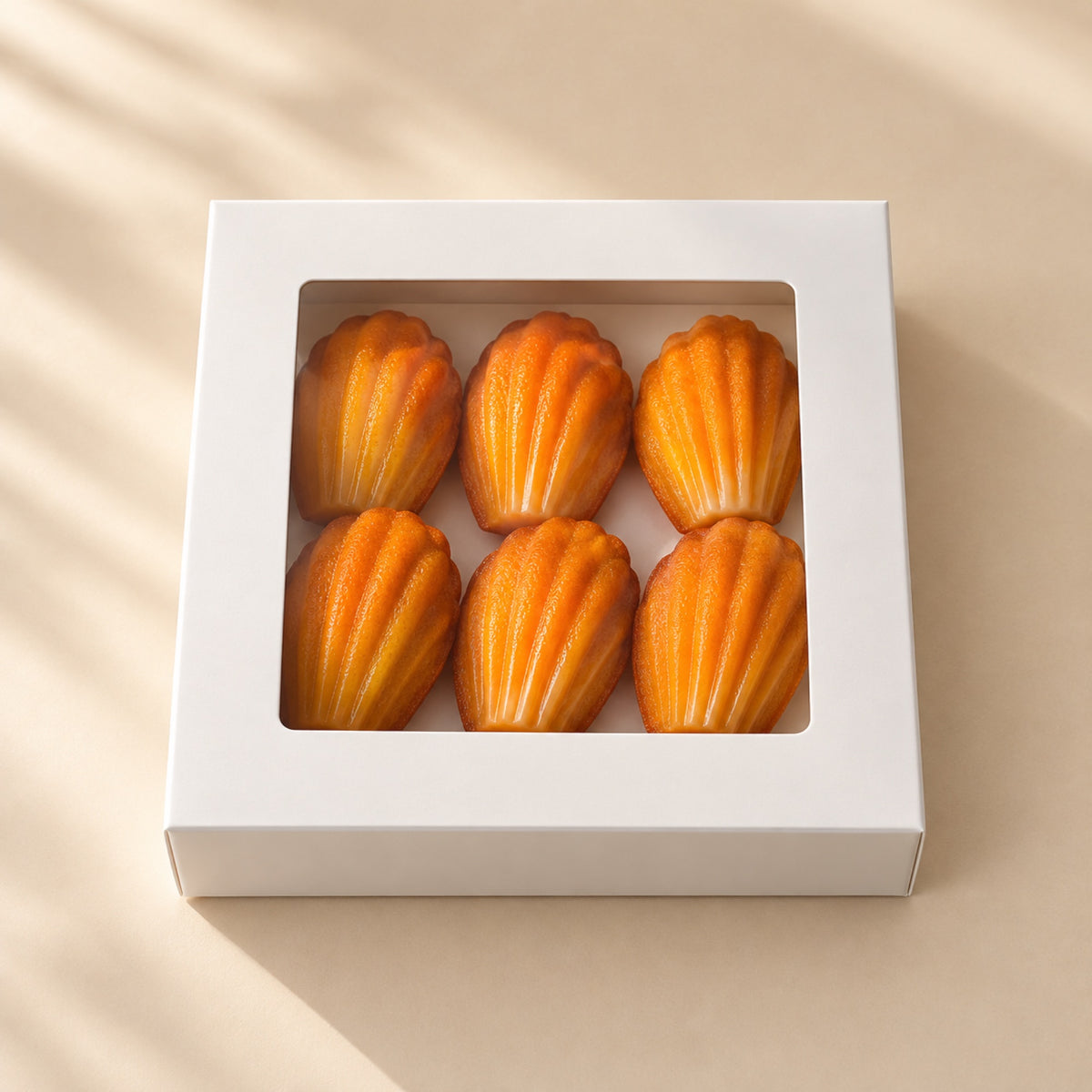 Sechs Madeleine-Pralinen mit Pistazie in einer weißen Box mit Sichtfenster, Ansicht von oben