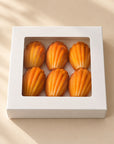 Sechs Madeleine-Pralinen mit Pistazie in einer weißen Box mit Sichtfenster, Ansicht von oben